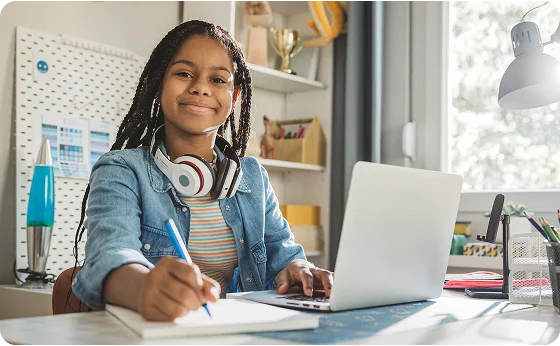 Estudiante tomando apuntes en casa con su portátil