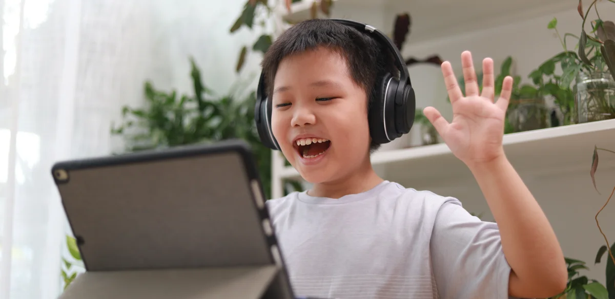Estudiante de primaria con unos auriculares negros mientras asiste a una clase en línea